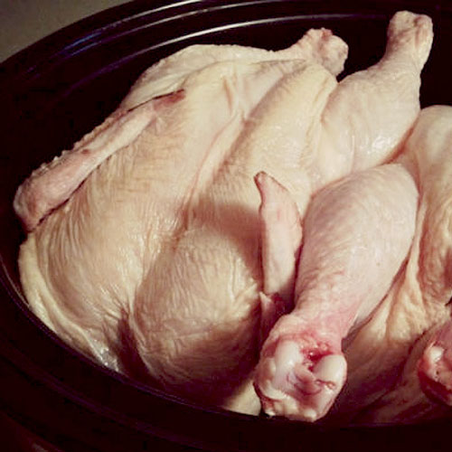 two raw chickens in black crock pot