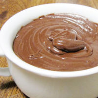 White bowl filled with creamy and smooth chocolate ganache frosting.