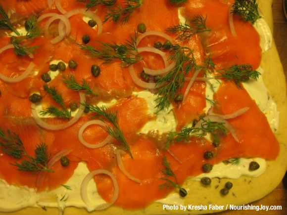 Ready for a scrumptious taste of spring? You'll love this pizza! It features lox (salt-cured salmon), fresh lemon, fresh dill, capers, sour cream, and spring onions. YUM! | TraditionalCookingSchool.com
