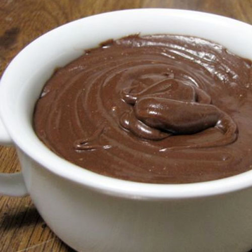 White bowl filled with creamy and smooth chocolate ganache frosting.