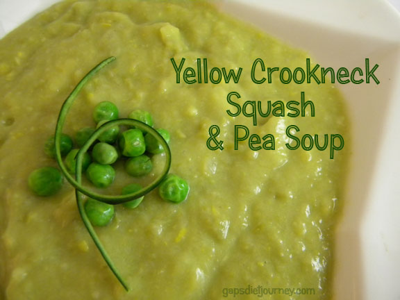 green soup with garnish of peas and a loop of squash peel