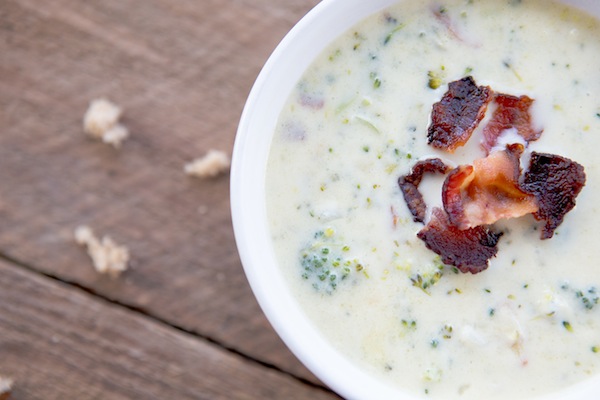 creamy cheesy soup with broccoli in it and crispy bacon pieces for garnish