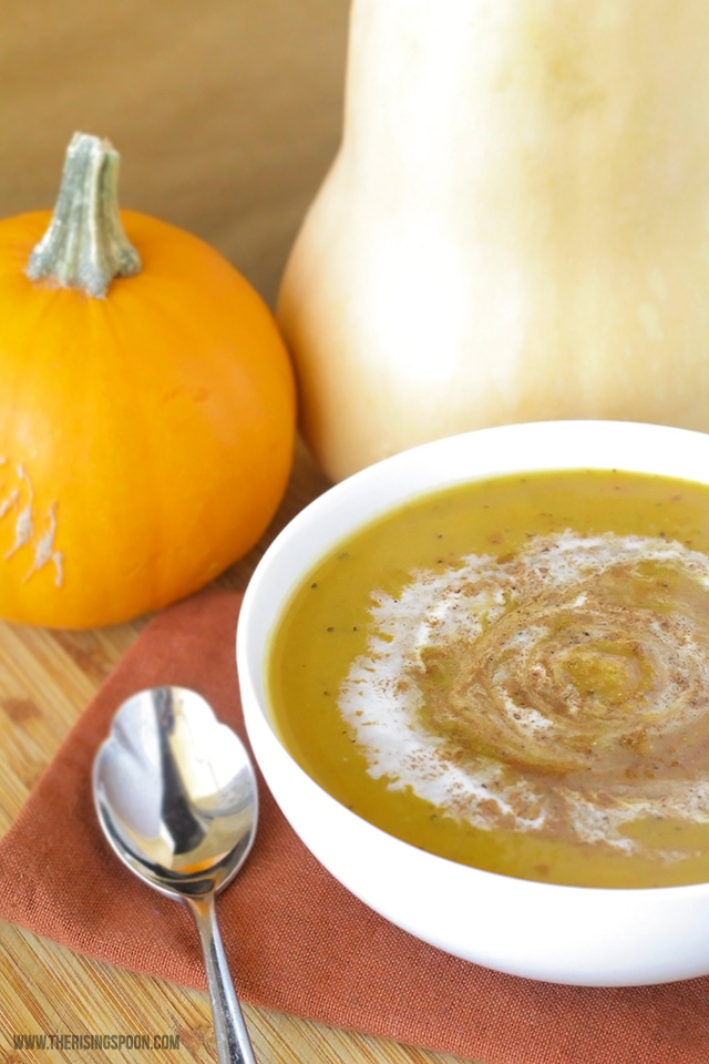 bowl of soup next to a pumpkin and squash