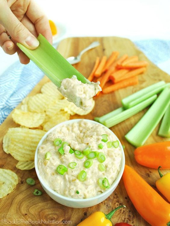 Onion and Shallot Dip with side of celery, carrots, peppers, chips on wooden cutting board
