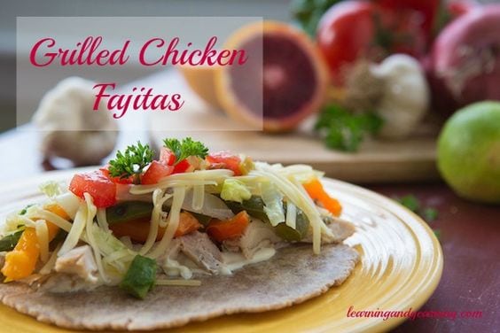 Grilled chicken fajitas with tortilla on a yellow plate with veggies on cutting board and pink text overlay