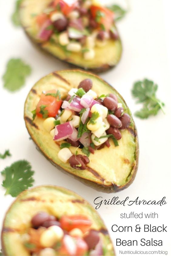 Grilled avocado with corn and black bean salsa and cilantro in background with black text overlay