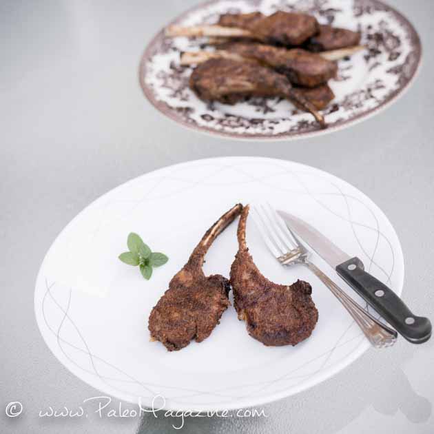 Crusted lamb chops on a plate with fork and knife with white text overlay