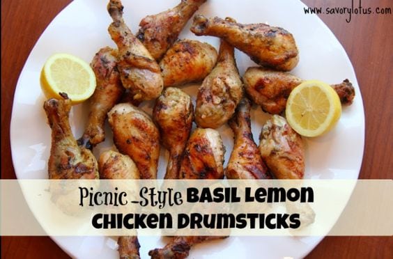 Basil lemon chicken drumsticks with lemon halves on a white plate with black text overlay