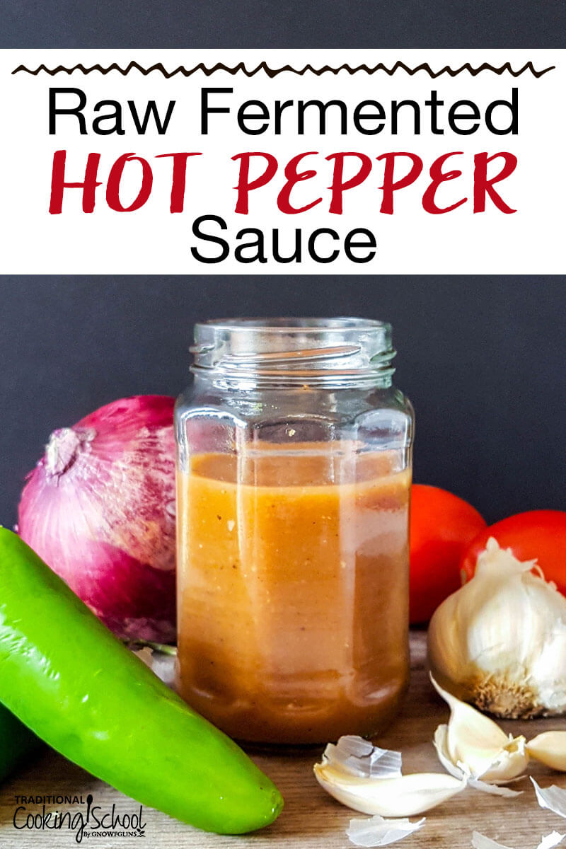 Homemade hot sauce in a small jar surrounded by garlic, hot peppers, onion, and tomatoes. Text overlay says: "Raw Fermented Hot Pepper Sauce"