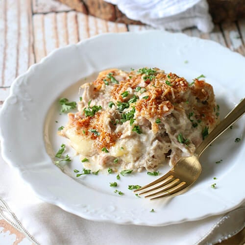 creamy casserole on white plate with gold fork