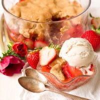 strawberry cobbler in bowl a la mode with spoon and fresh red flowers