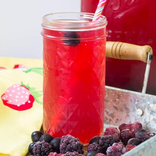 probiotic mixed berry switchel in a glass with a pink-striped paper straw