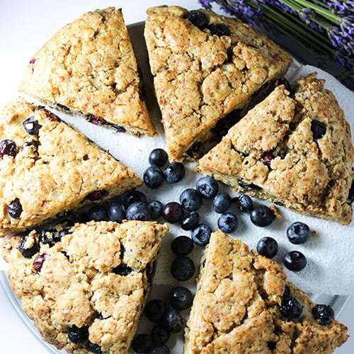 plate of six blueberry scones with blueberries and lavender scattered around