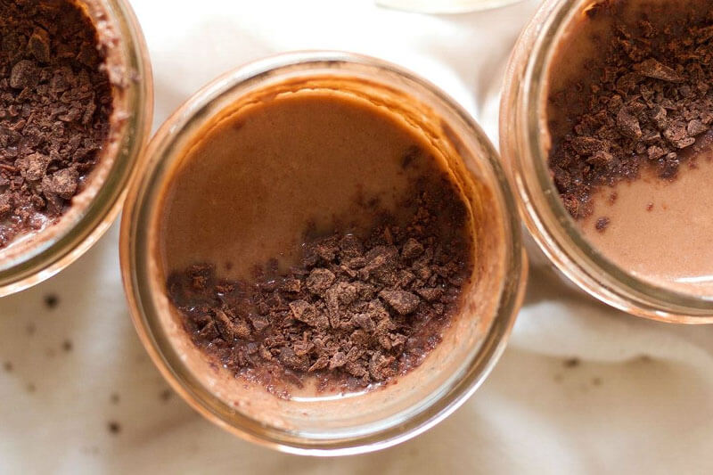 glass jars of chocolate pudding topped with chocolate shavings