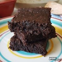 three fudgey sourdough brownies stacked on a colorful plate