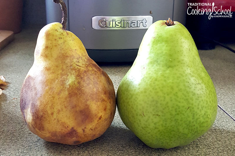 one very ripe pear with bruised spots and one bright green, unripe pear