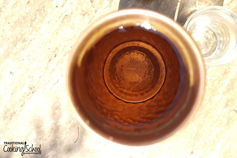 looking inside a copper water bottle on a countertop next to a glass of water