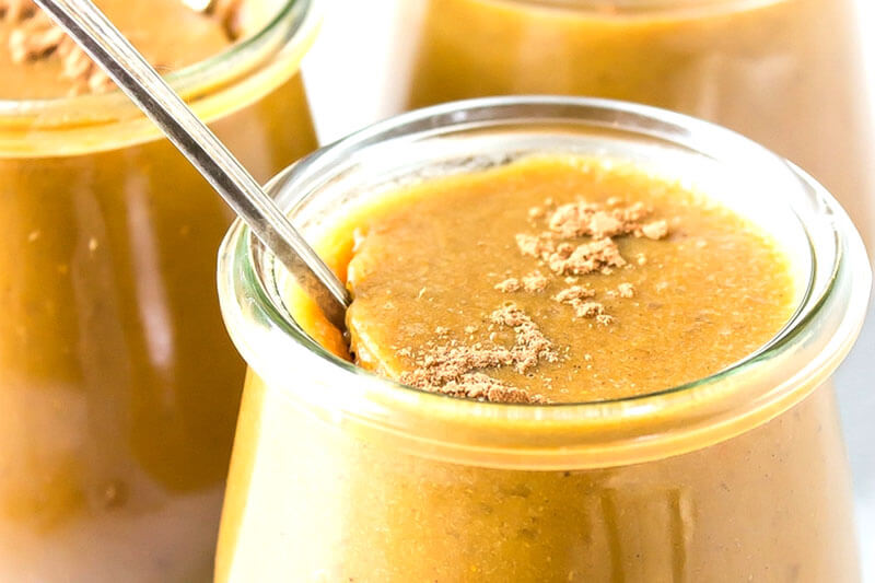 glass jars of easy healthy pumpkin custard with spoon and spices sprinkled on top