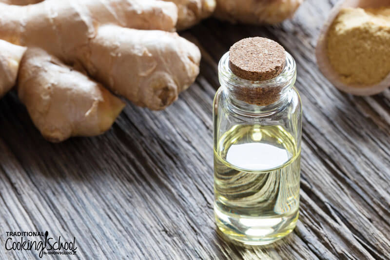 bottle of ginger root essential oil next to ginger roots