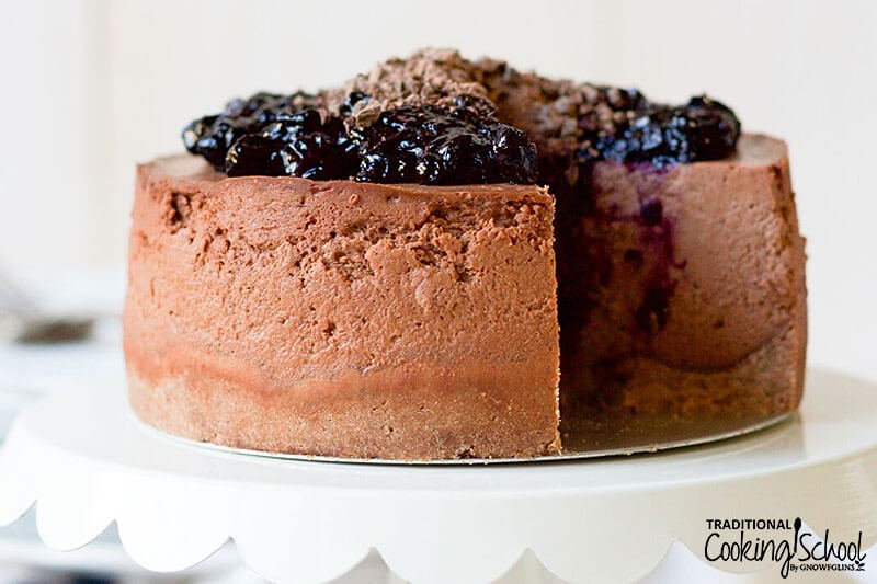 beautiful chocolate cheesecake with blueberry sauce on top and a slice cut out of it