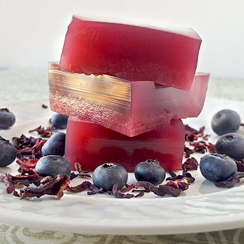 stack of three gelatin gummies with herbs and blueberries scattered around
