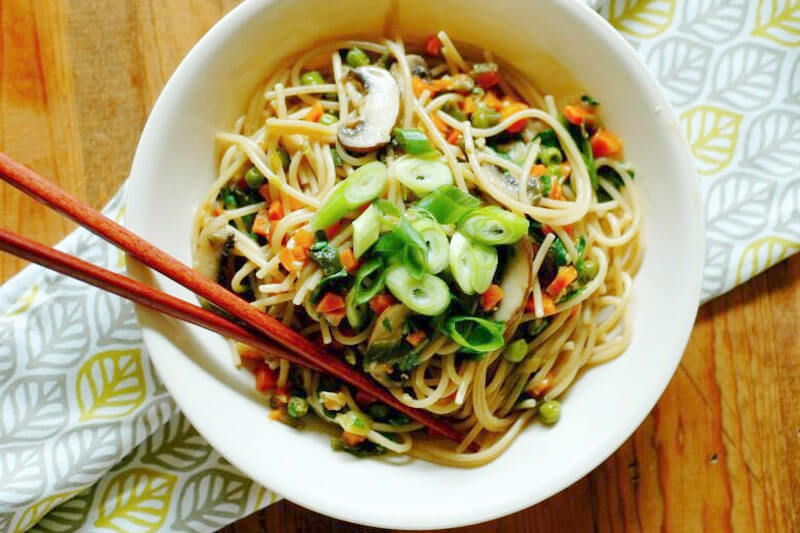 white bowl of vegetable lo mein with chopsticks