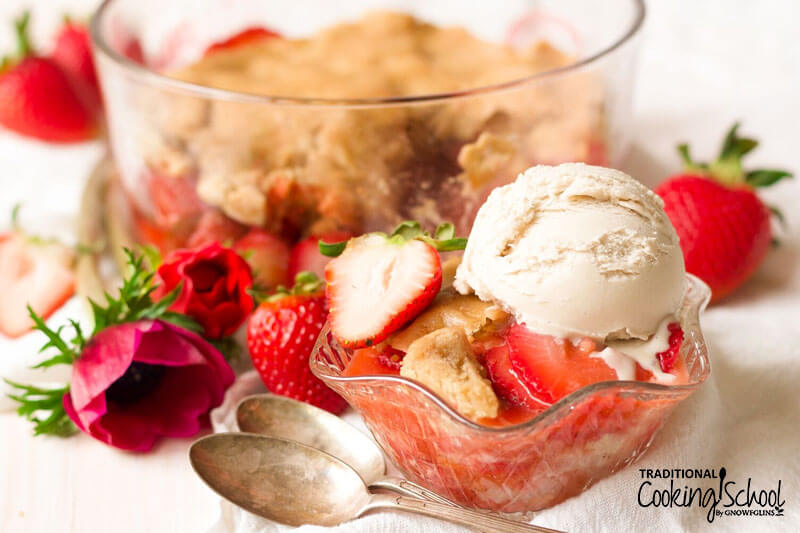 decorative glass bowl of strawberry cobbler topped with ice cream