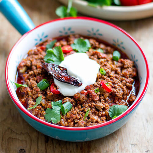 big bowl of healthy chili, garnished with chives, parsley, sour cream, and a sundried tomato