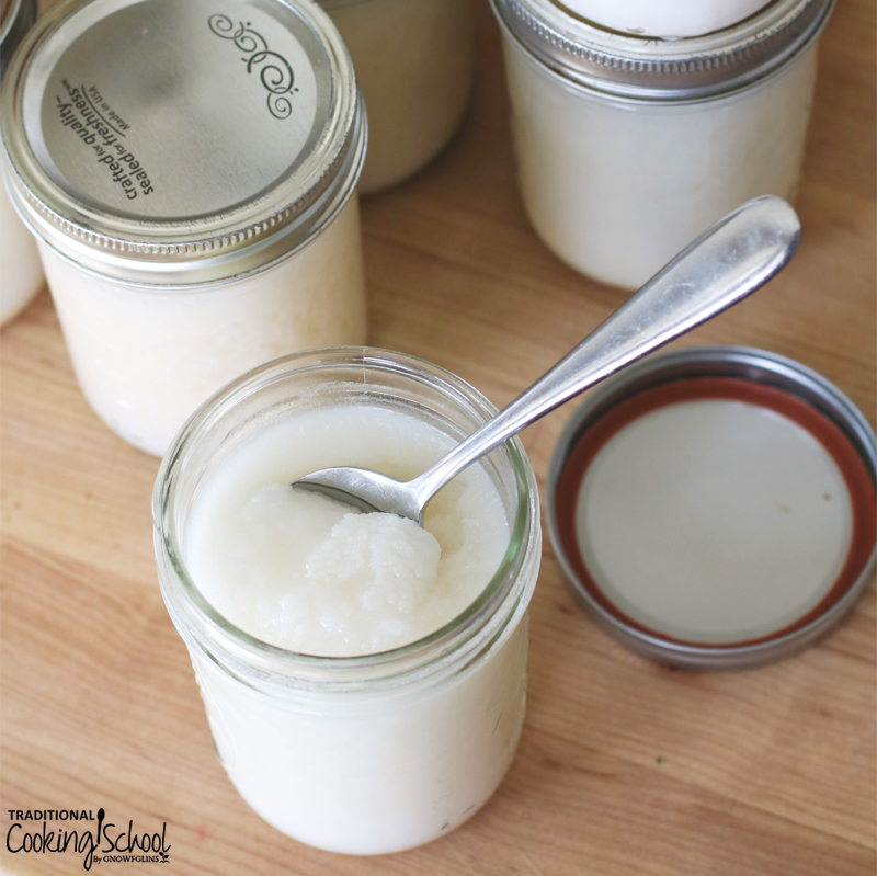 pint size Mason jars of snow white lard, one open with a spoon scooping some out