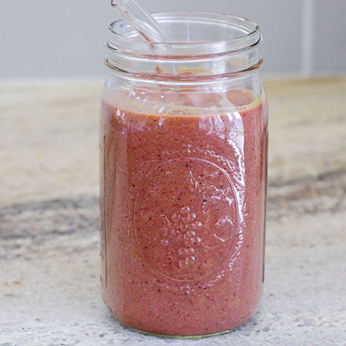 beautiful pink-colored smoothie in quart-sized Mason jar with glass straw