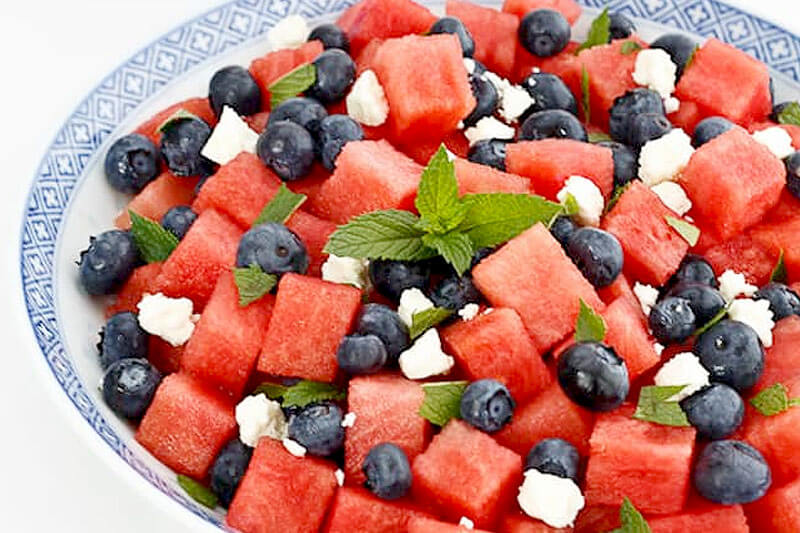 big bowl of watermelon blueberry fruit salad with feta cheese chunks and mint for garnish