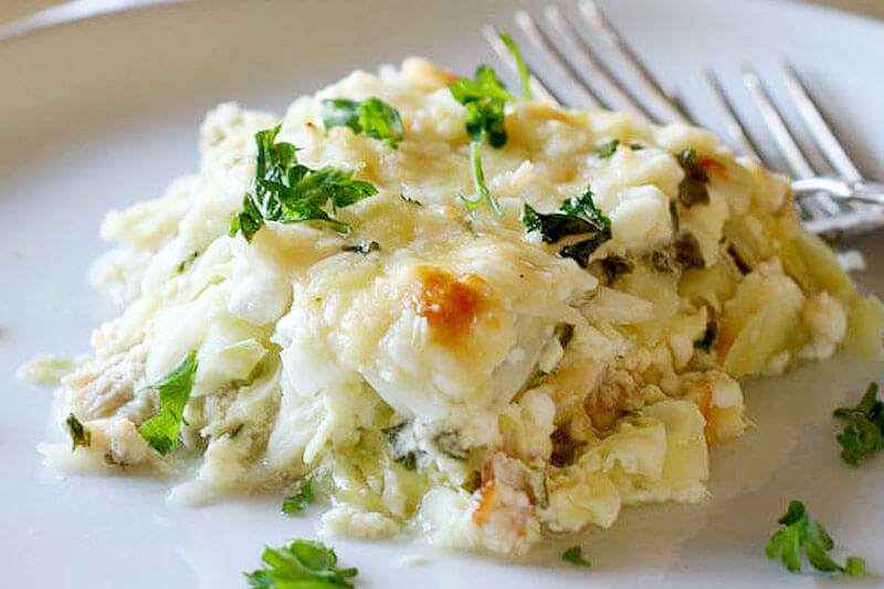 a generous serving of chicken cabbage casserole on a plate, garnished with fresh herbs, with two forks in the background