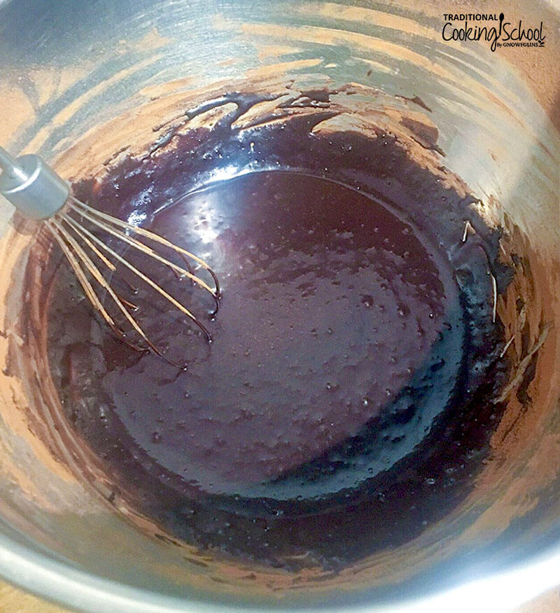 whisking together maple syrup, warm butter, and cocoa powder in a stainless steel bowl to make baked chocolate oatmeal