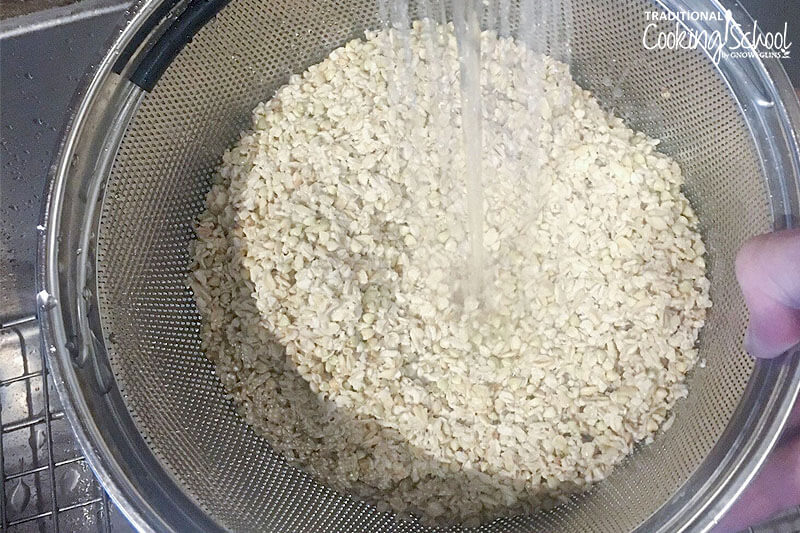 rinsing a mixture of soaked oats in a fine-mesh colander under running water