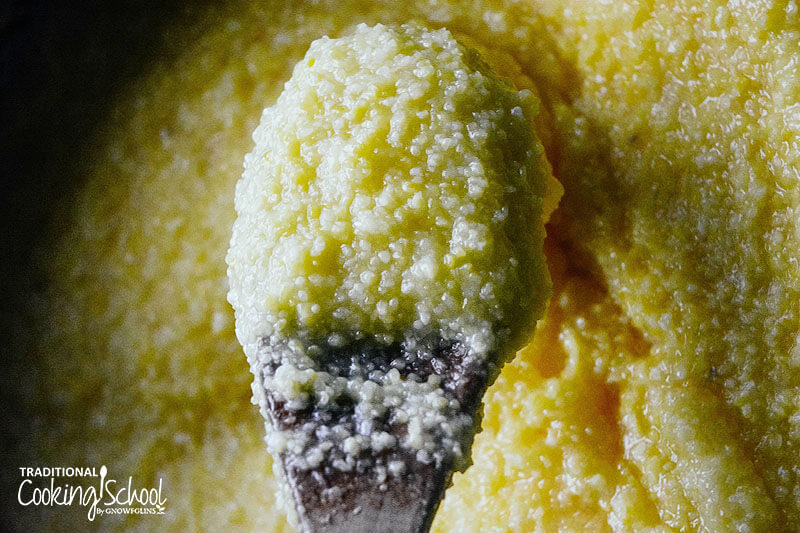 close-up shot of a wooden spoon scooping up creamy polenta so you can see the silky texture