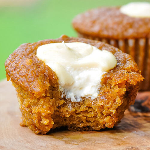 close-up shot of a pumpkin muffin with a bite taken out of it to reveal a cream cheese filling