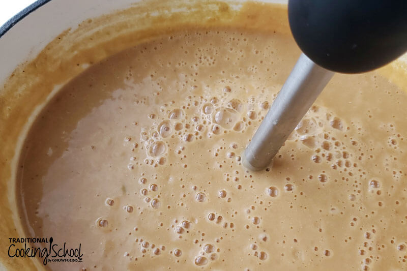 an immersion blender blending up lentil soup so it is smooth