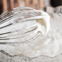 close-up shot of a whisk that has been used to make whipped cream so that it is covered in foamy cream