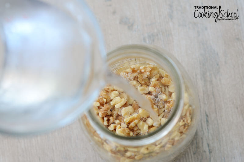 Raw nuts in a mason jar covered with water for soaking.