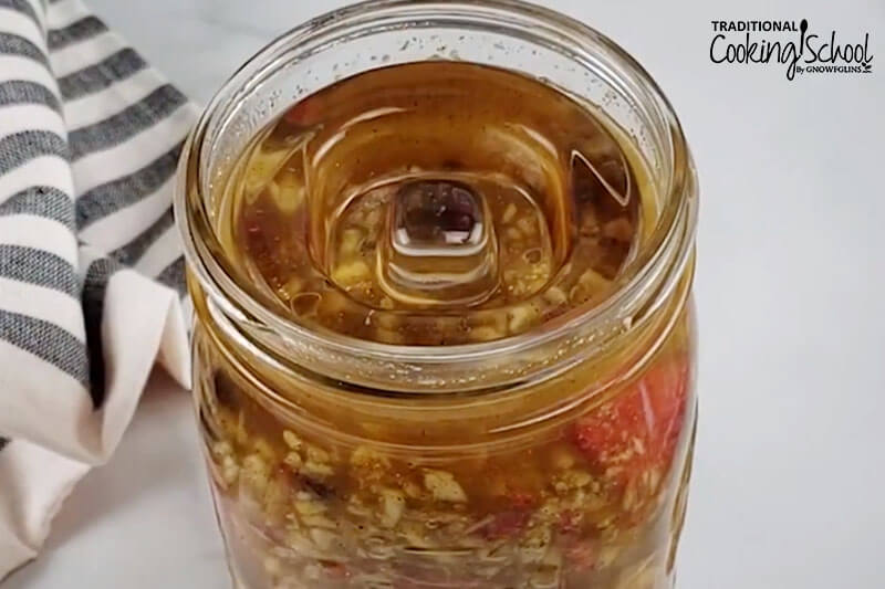 quart-sized Mason jar of fermented apple chutney with a glass weight at the top