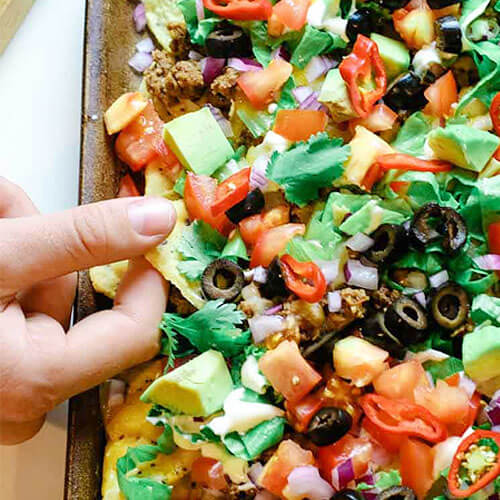 sheet pan of nachos with hand