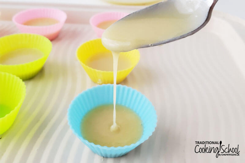 spooning white chocolate mixture into mini silicone muffin cups as candy molds