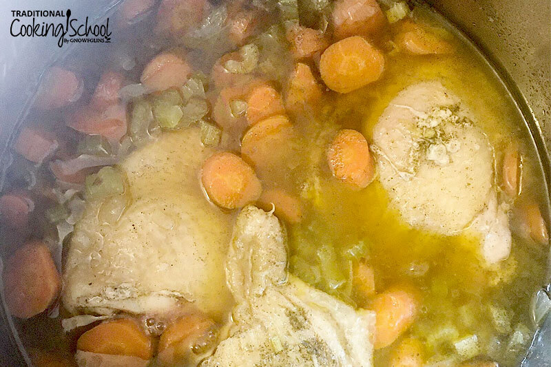 overhead shot of chicken pieces and veggies cooking in broth in a pot