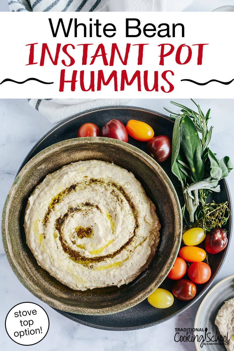 hummus garnished with a swirl of olive oil and za'atar in a bowl with tomatoes and herbs around, with text overlay: "White Bean Instant Pot Hummus (stove top option!)"