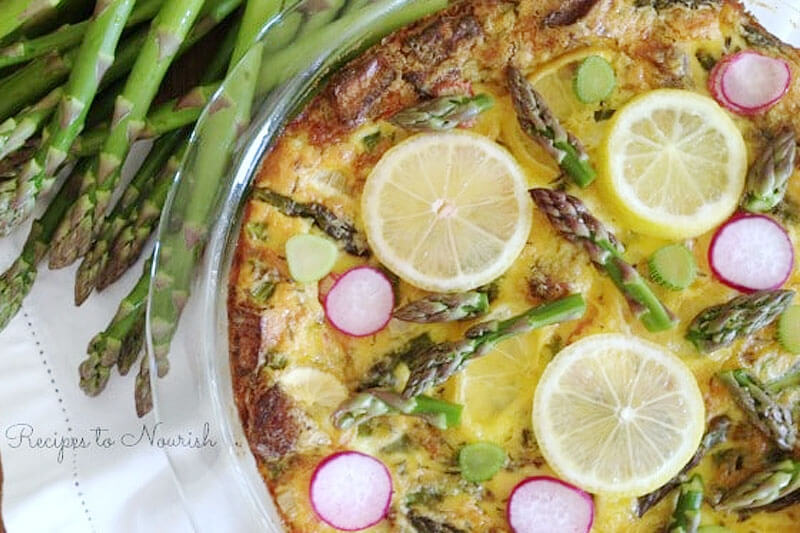 crustless spring quiche with slices of lemon, radish, and asparagus arranged artfully on top