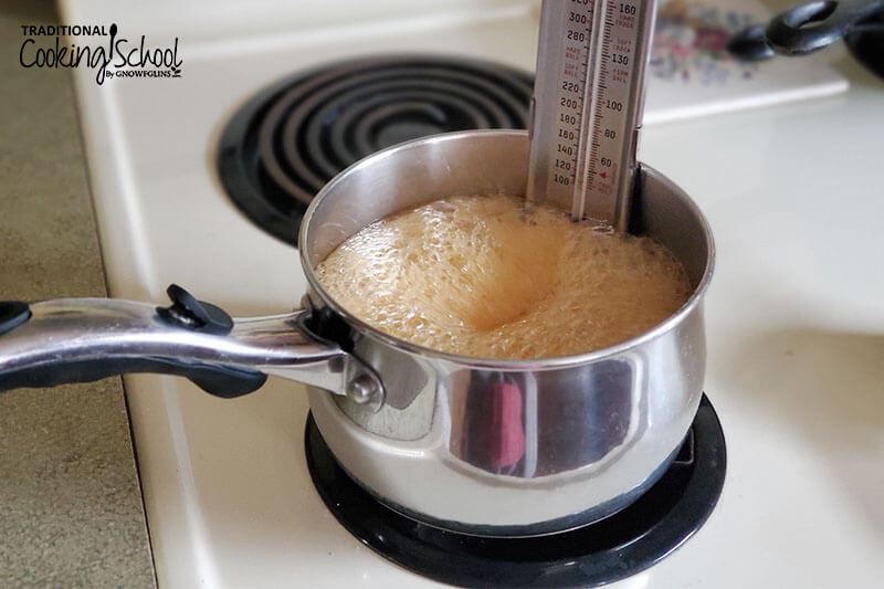 boiling honey in a pot on the stove with a candy thermometer