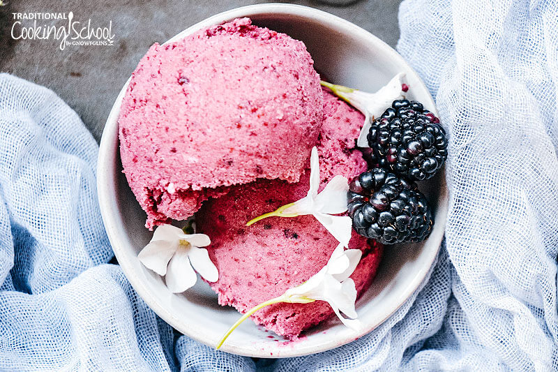 dairy-free blackberry ice cream in a bowl with fresh blackberries and white flowers for garnish