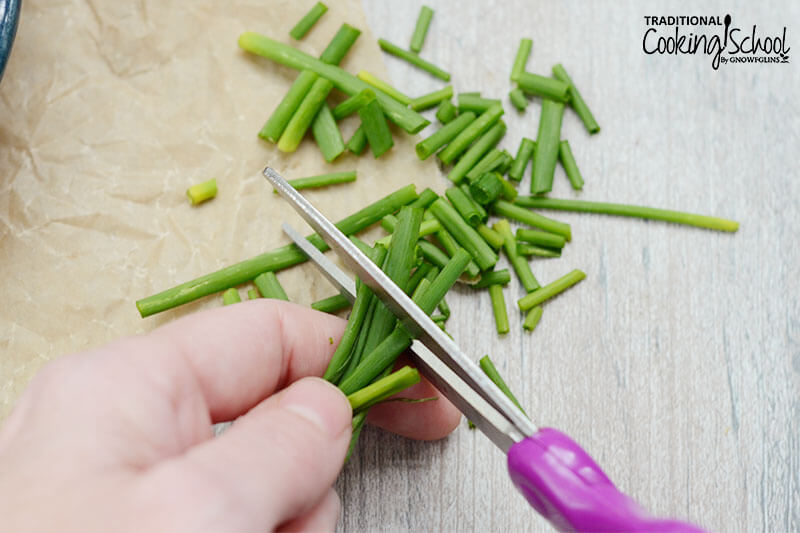 woman using a pair of purple scissors to chop fresh chives