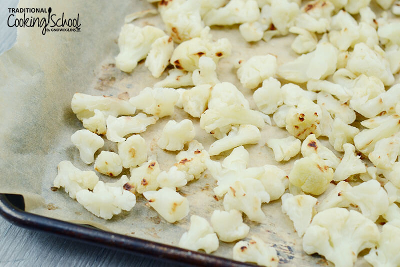 roasted cauliflower florets on a parchment paper lined baking tray