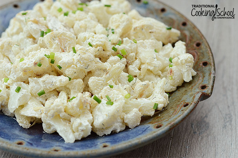 cauliflower potato salad topped with fresh chives in a ceramic dish